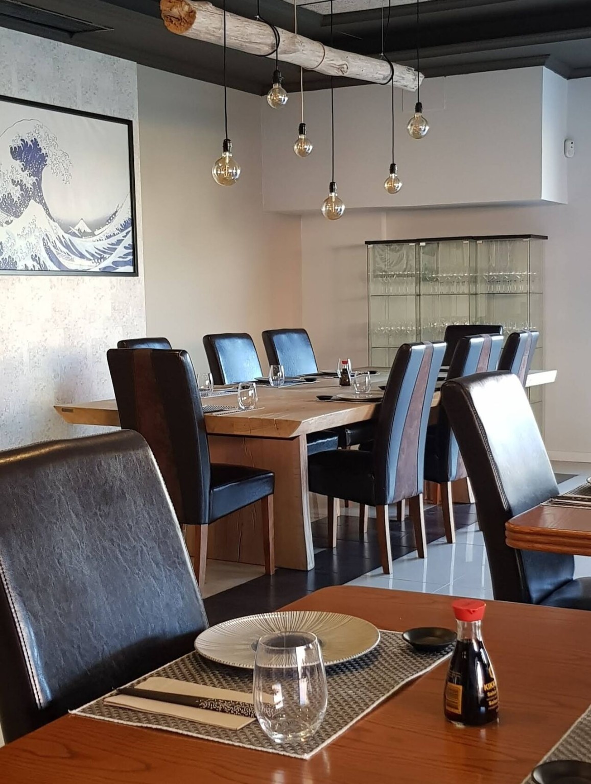Interior de Hasaki con mesas de madera, asientos tapizados y decoración vegetal